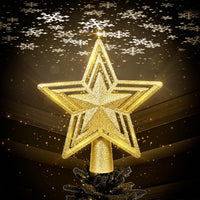 Stella gold glitter star tree topper glowing against a dark background with snowflakes