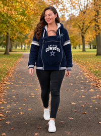 Mom walking through an autumn park wearing the Dallas Cowboys carrier hoodie with her baby