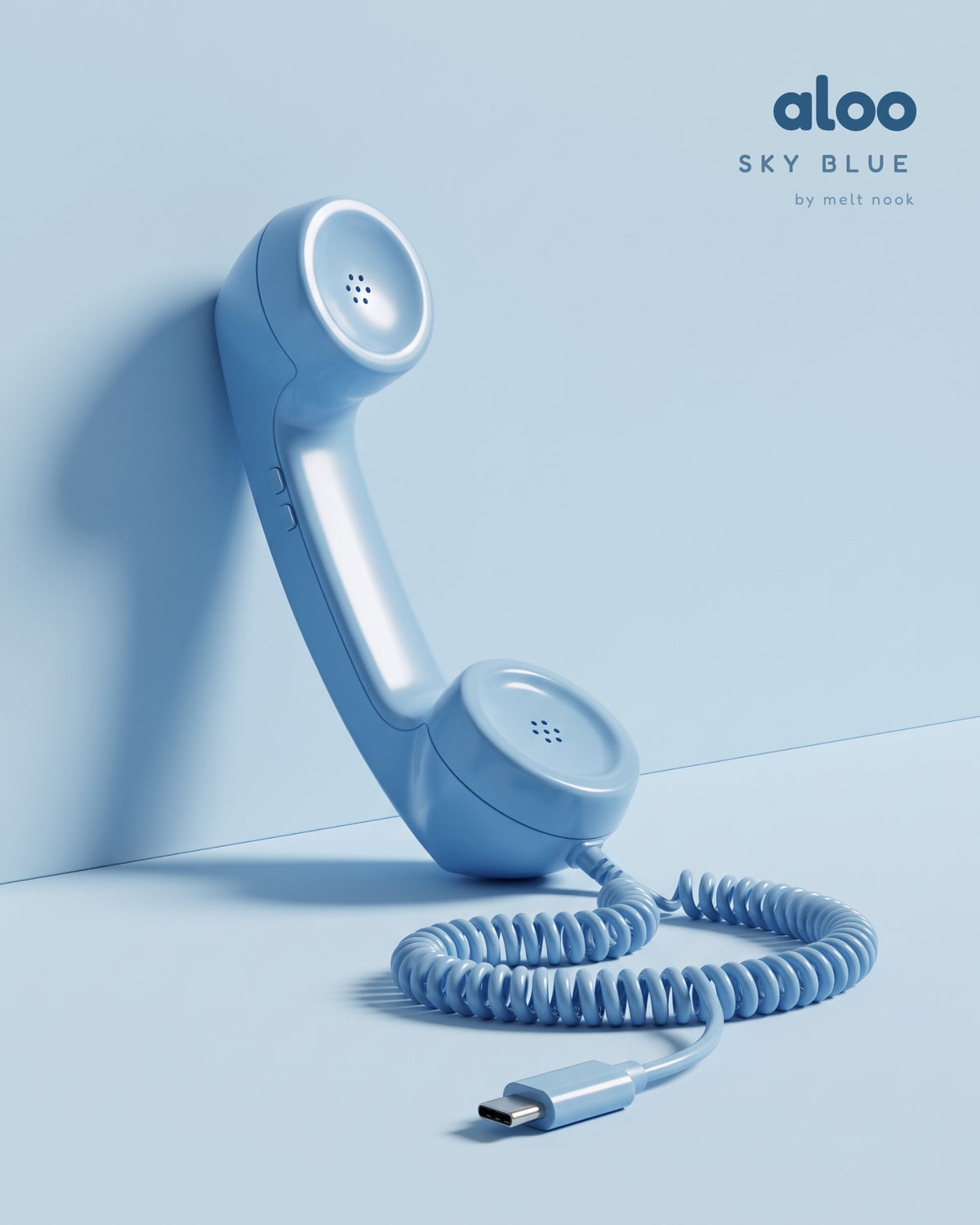Aloo in sky blue standing against a sky blue wall, its coiled USB-C cord on the floor