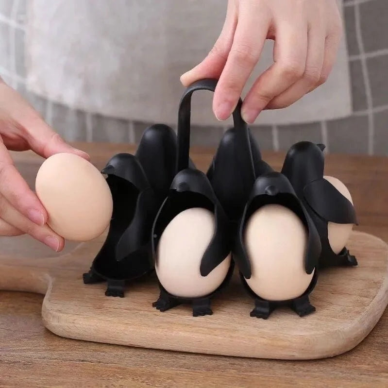 Two hands loading an egg into one of the six penguins, holder held by the arched handle